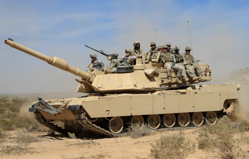 M1 Abrams tank with soldiers riding on it